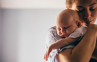 Parent standing up cradling young baby