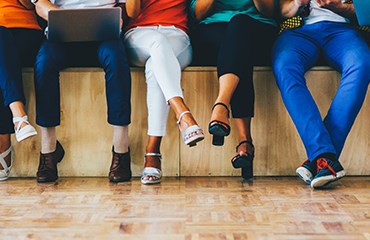 Group of people sitting on a stage with just their legs visible 