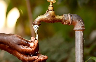 Person using outdoor tap to wash hands