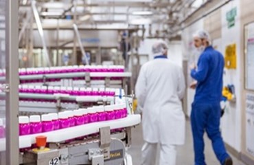Worker in a blue boiler suit and worker in white lab coat talking in a Gaviscon factory