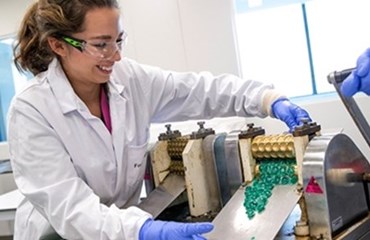 Smiling lab technician working in a lab operating a Strepsil pressing machine